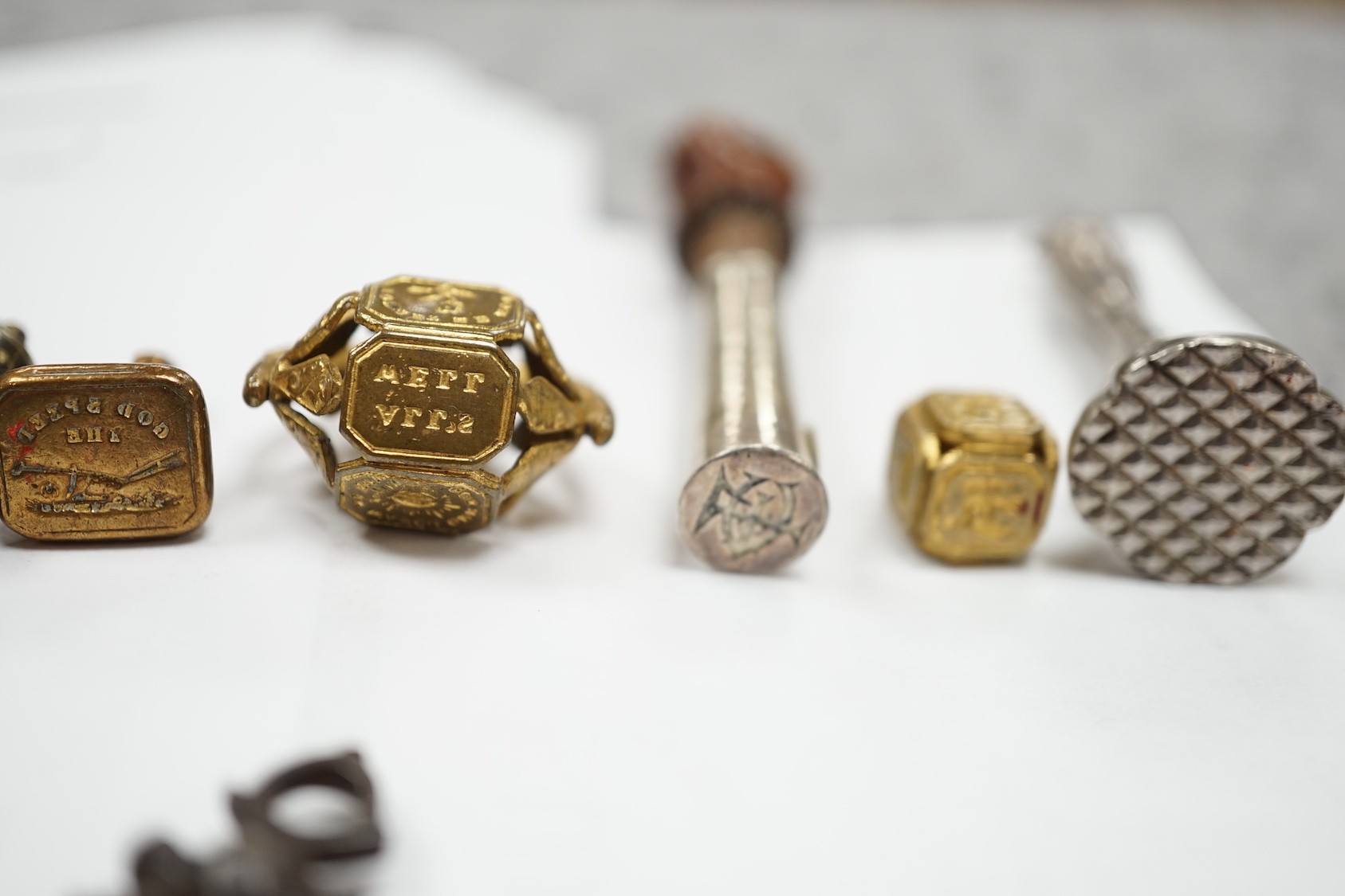 A group of twenty-five steel, gilt metal or nickel fob or desk seals, mostly 19th-century, including a steel swivel seal, a seal with boxwood finial modelled as a hand holding a ball and a nickel multi seal